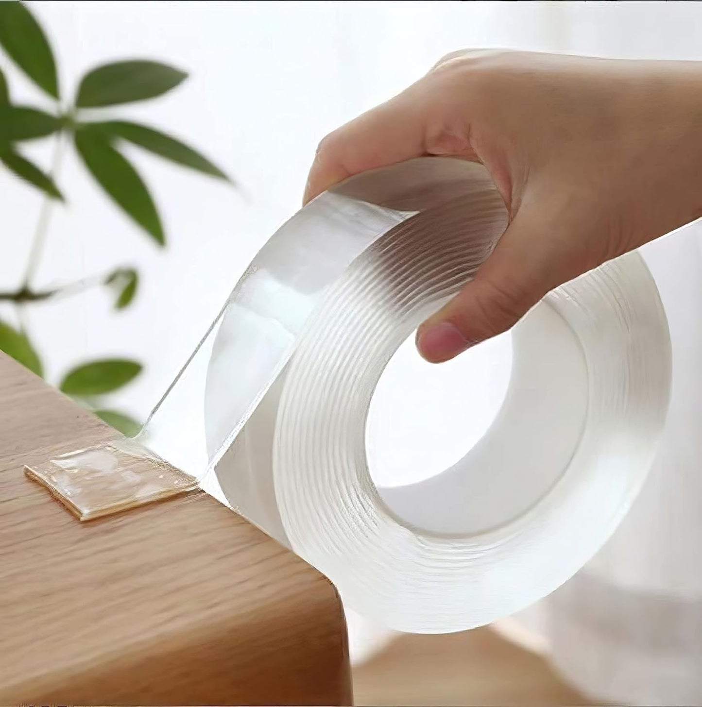 Hand holding a roll of clear tape with a blurred background